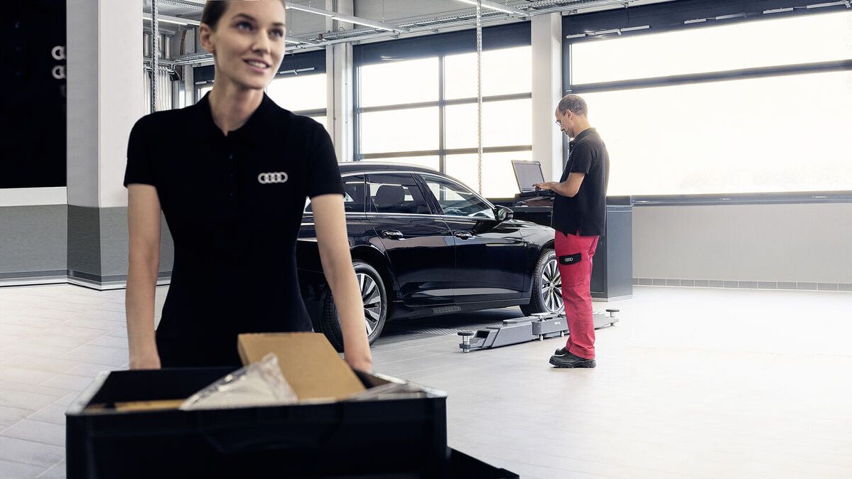 Ein Audi Service Berater führt mit einem Kunden vor einem Audi ein Gespräch