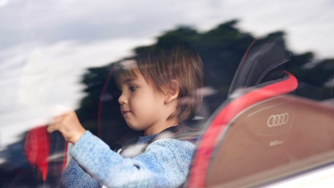 Kind sitzt in einem roten Audi Kindersitz