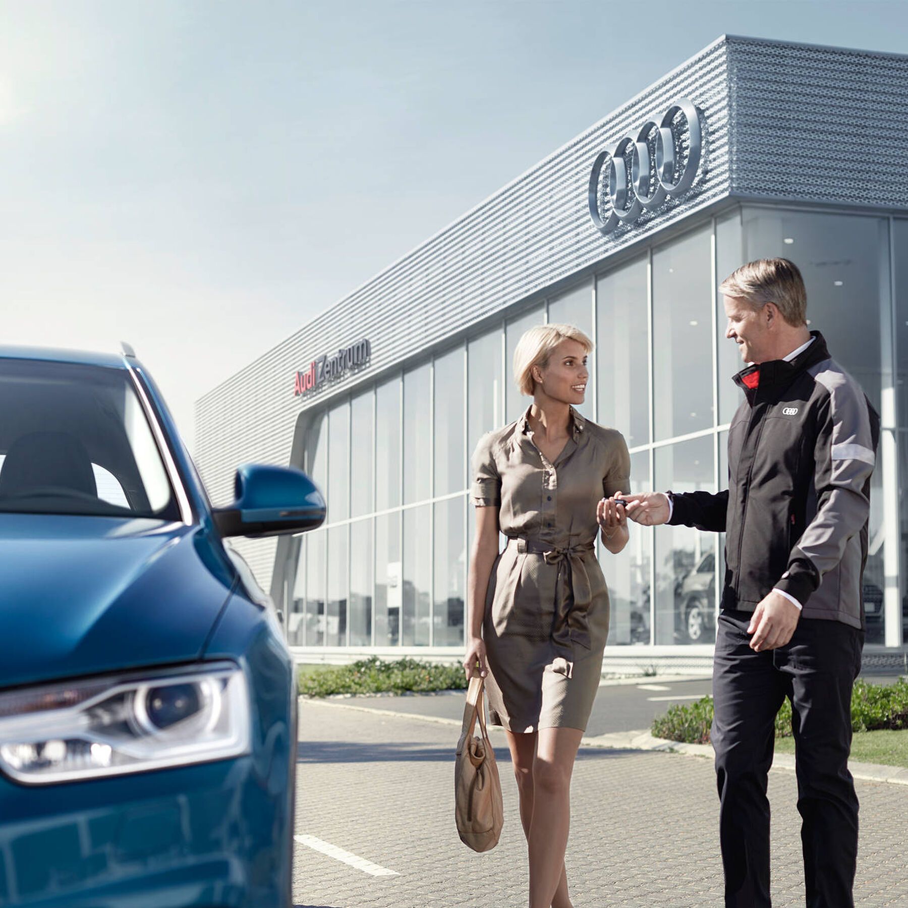 Ein Audi Mitarbeiter überreicht einer Frau den Schlüssel zu ihrem neuen Audi 
