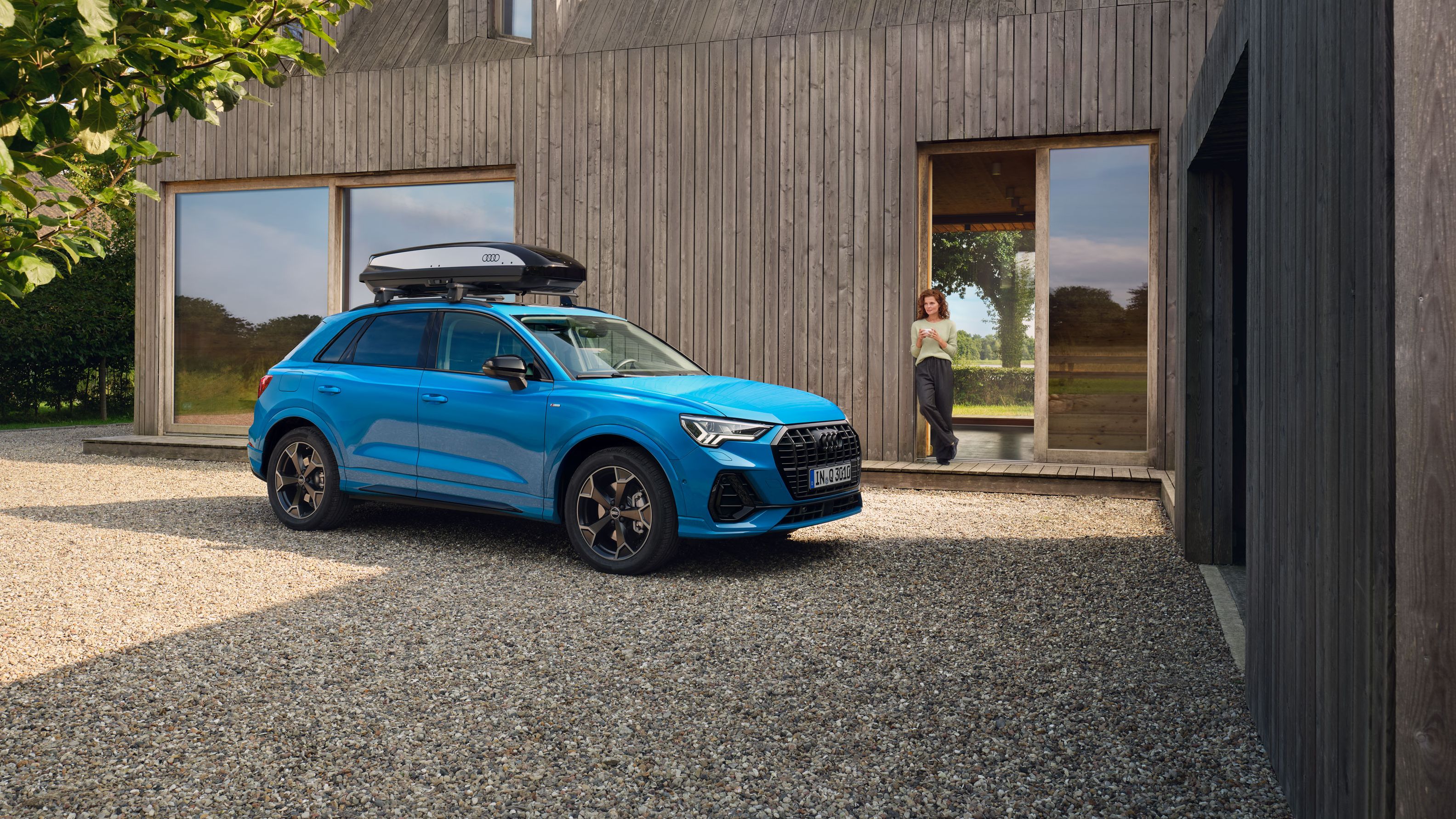 Blauer Audi mit Dachbox parkt in einer Einfahrt