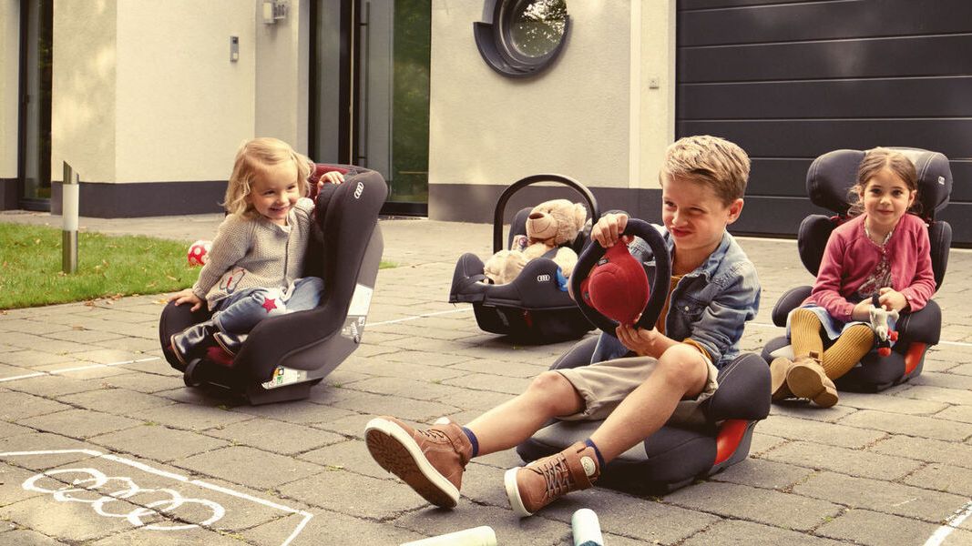 Kinder sitzen in ihren Audi Kindersitzen
