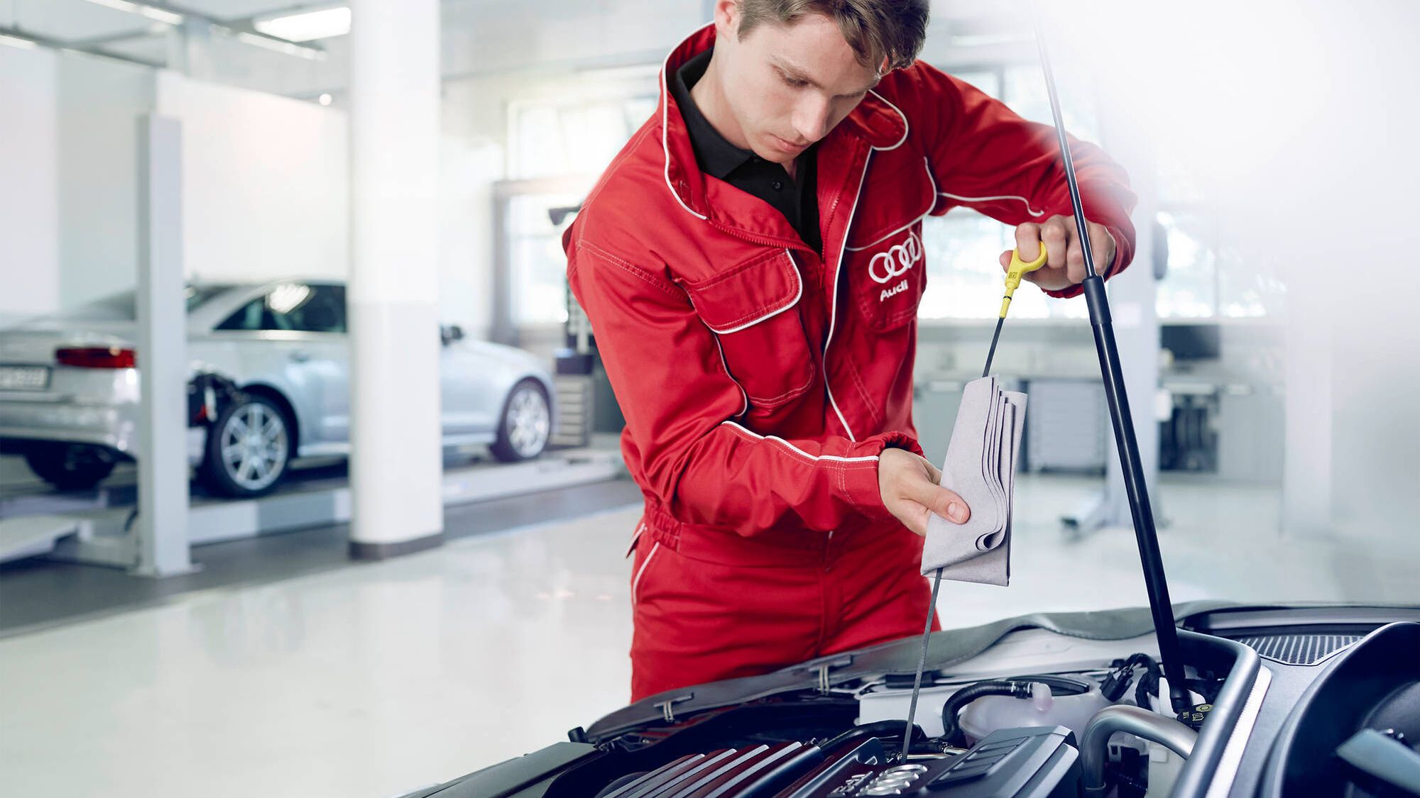 Zu sehen ist ein Mechaniker beim Ölstand Prüfen eines Audi Fahrzeuges