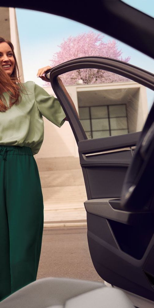 Eine Frau steigt lächelnd in ihren Audi Q3 ein.