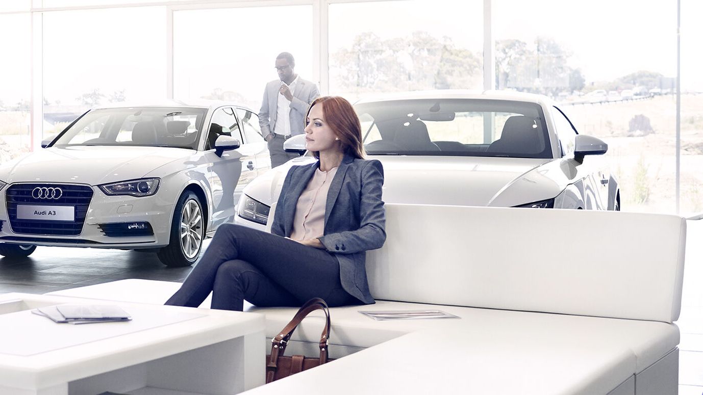 Eine Frau sitzt im Schauraum eines Audi Händlers