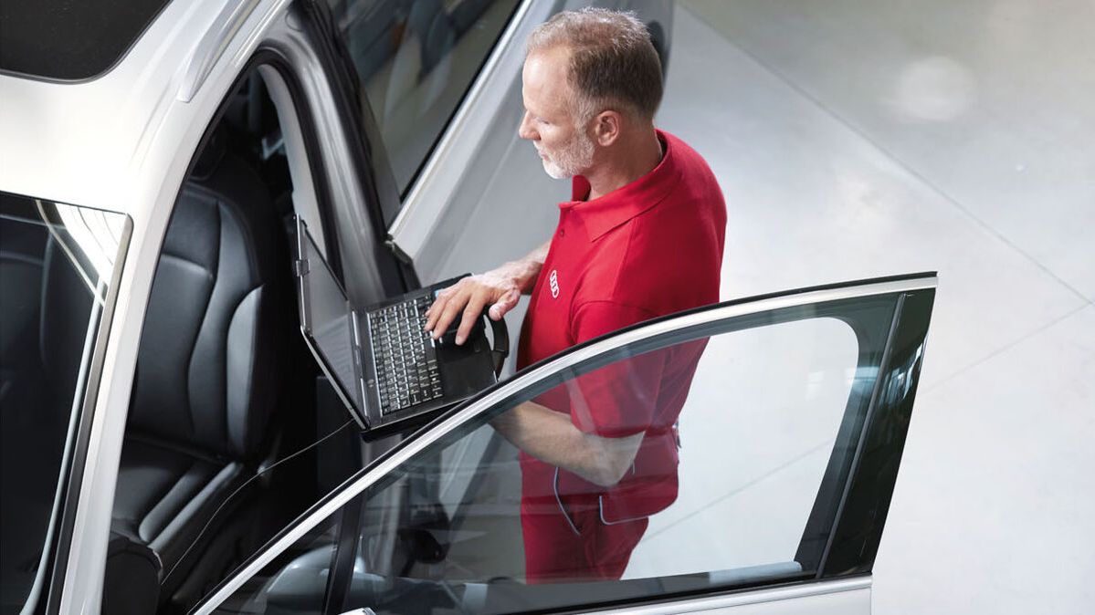 Ein Audi Service Techniker mit seinem Laptop bei der Überprüfung