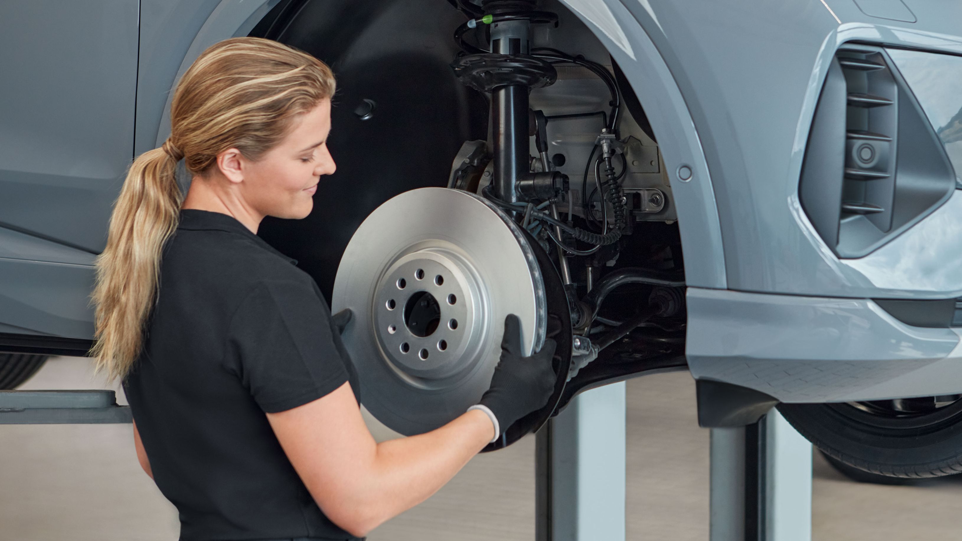 Eine Audi Service Technikerin wechselt die Bremsscheiben bei einem Audi Elektroauto
