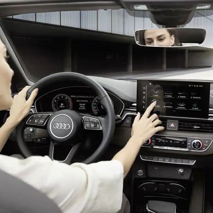 Eine Frau sitzt in einem Audi und  bedient Audi connect 