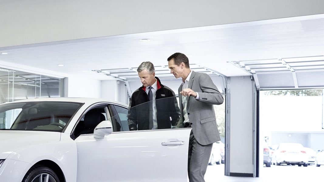 Zwei Männer inspizieren einen weißen Audi