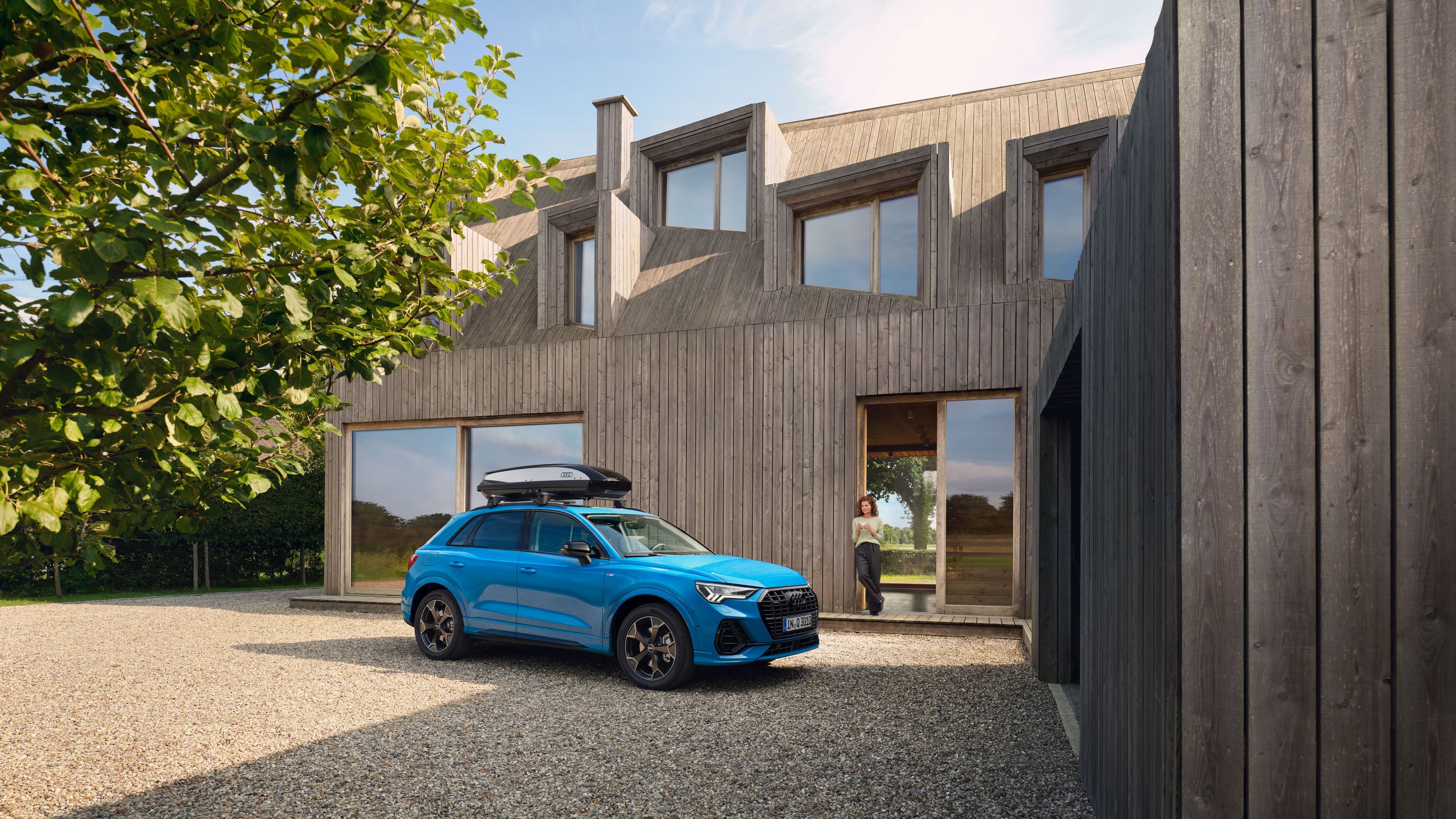 Blauer Audi mit Dachbox parkt in einer Einfahrt
