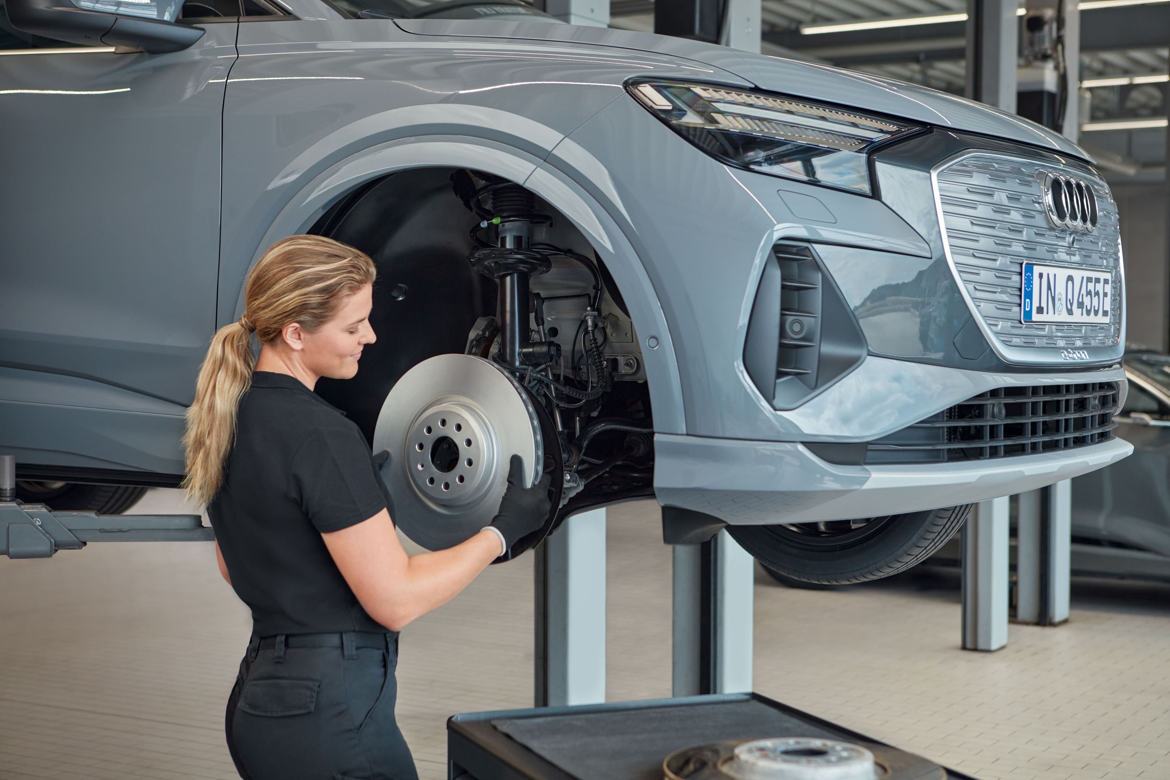 Eine Audi Service Technikerin wechselt die Bremsscheiben bei einem Audi Elektroauto