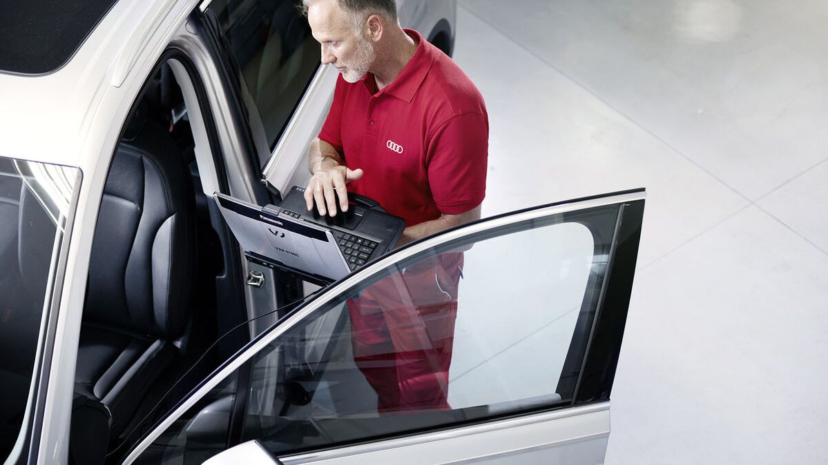 Ein Audi Service Partner steht neben der offenen Fahrertür eines Audi