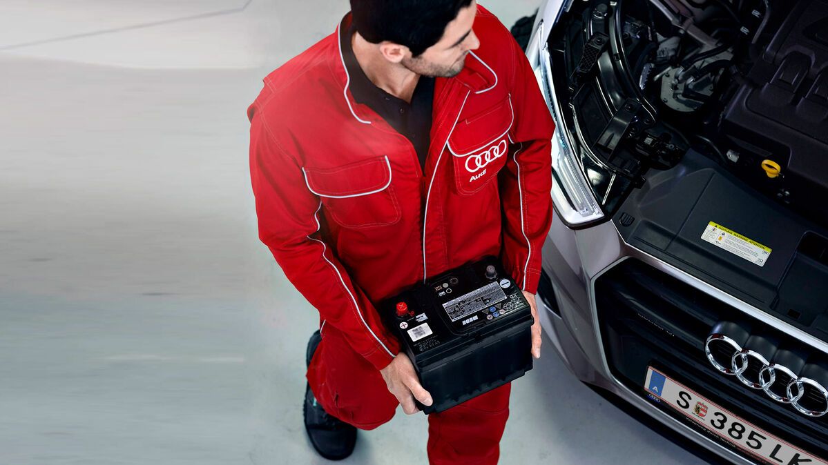Ein Audi Service-Techniker trägt eine Batterie zu einem Audi