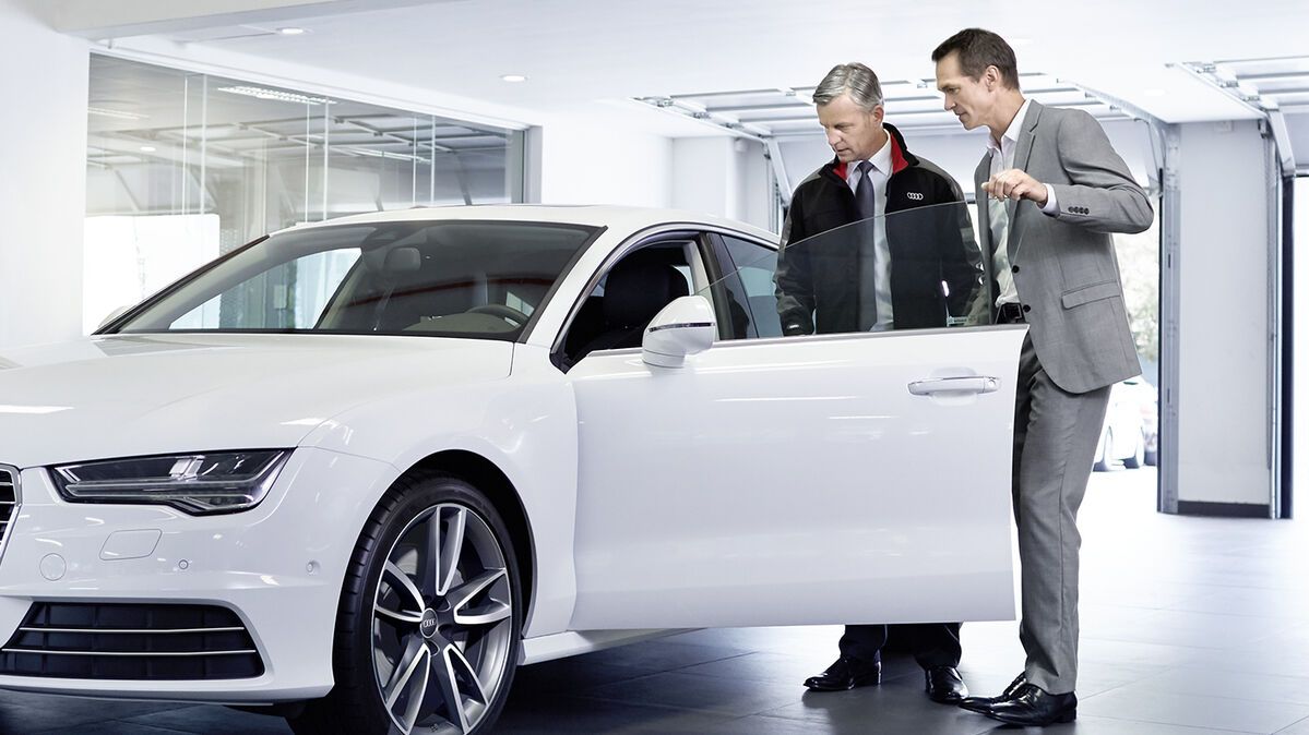 Zwei Männer stehen neben einem Audi im Audi Showroom