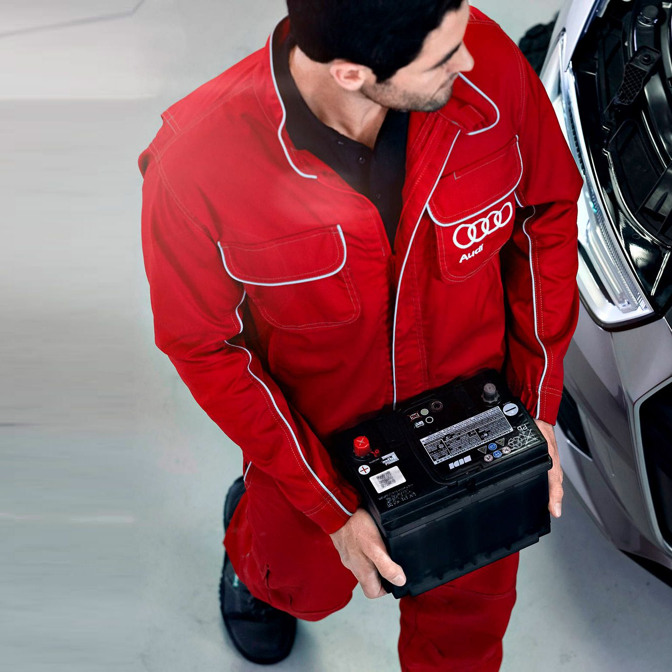 Ein Audi Service Techniker beim Tausch einer Starterbatterie