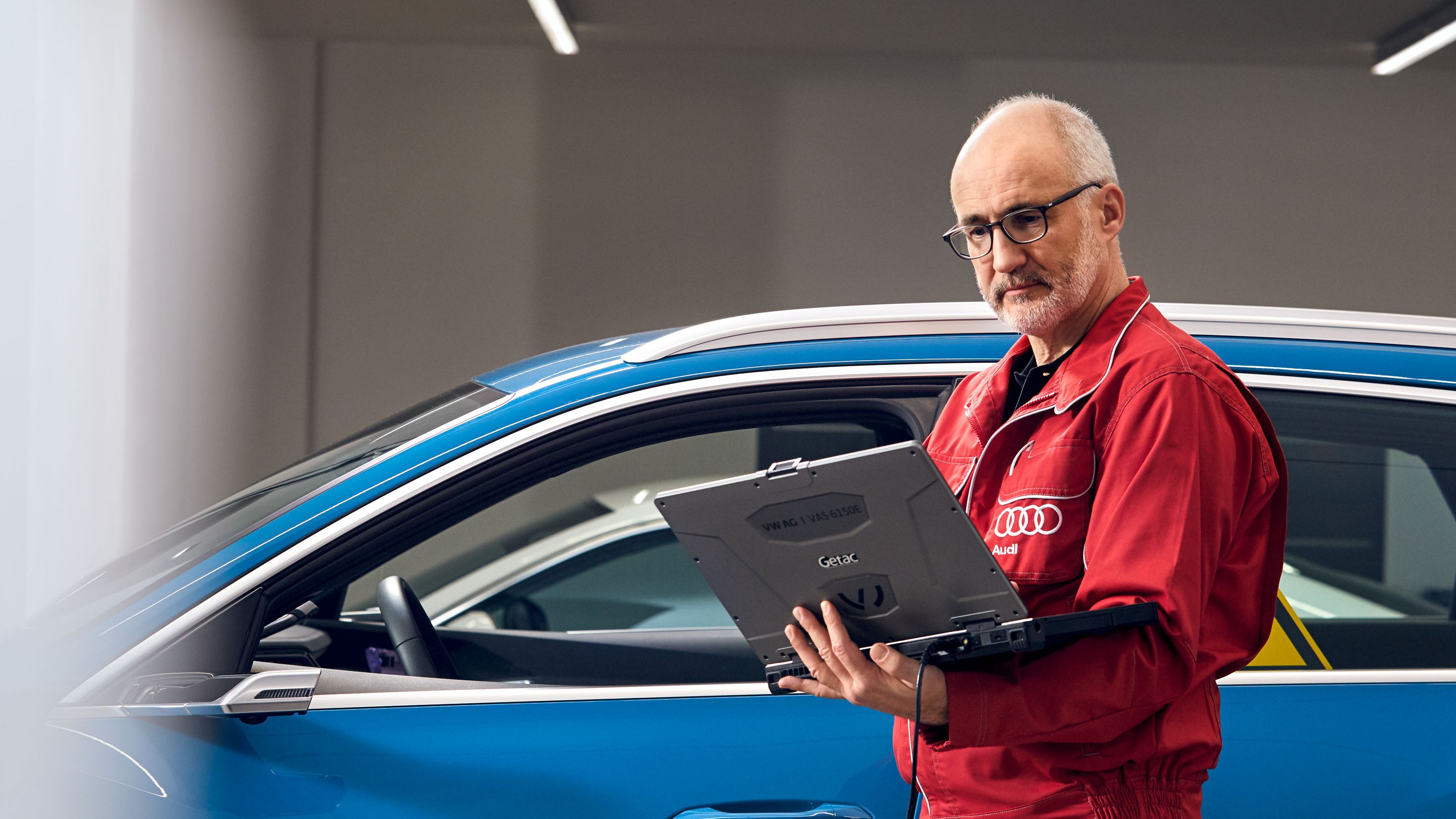 Ein Audi Service Techniker mit Laptop vor einem Audi