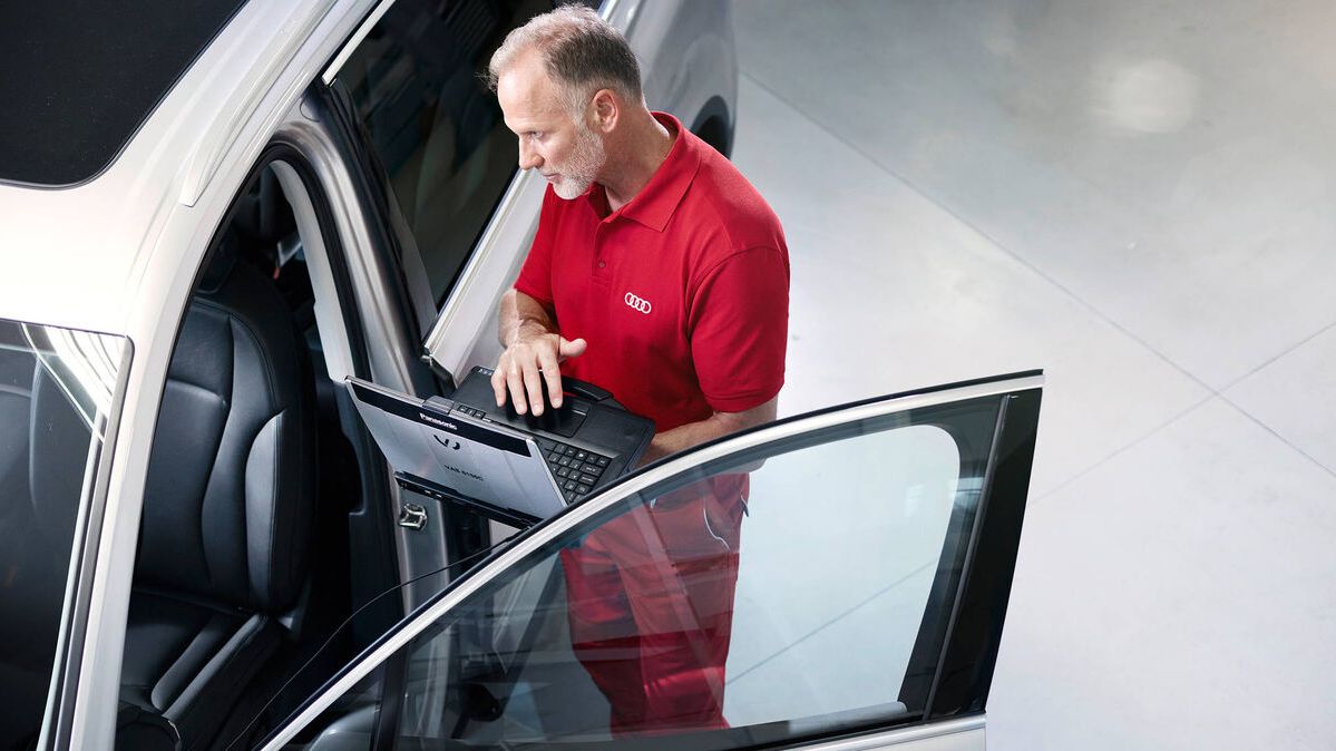 Ein Audi Techniker mit seinem Laptop vor einem Audi