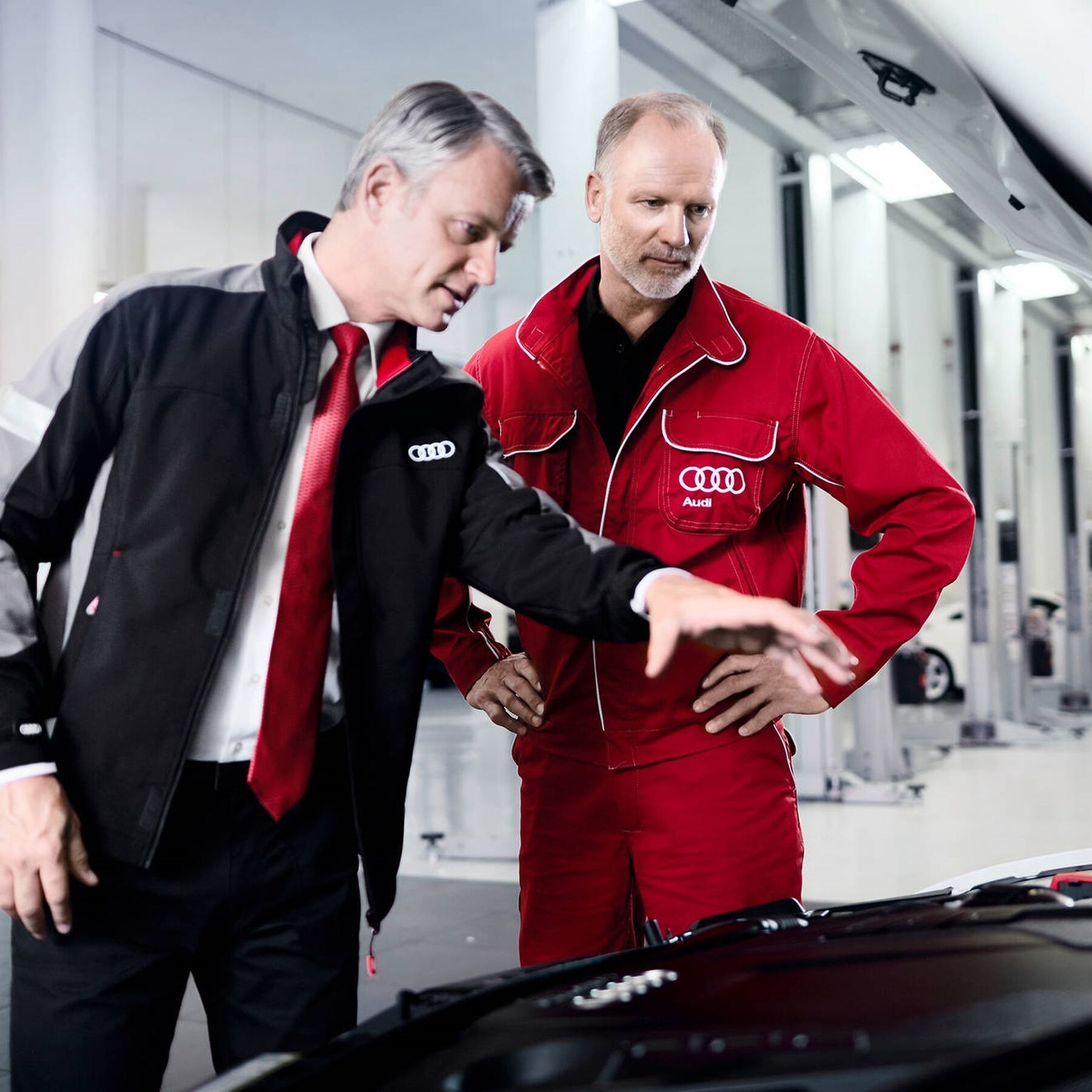 Audi Mitarbeiter zeigt auf Motorhaube von Audi