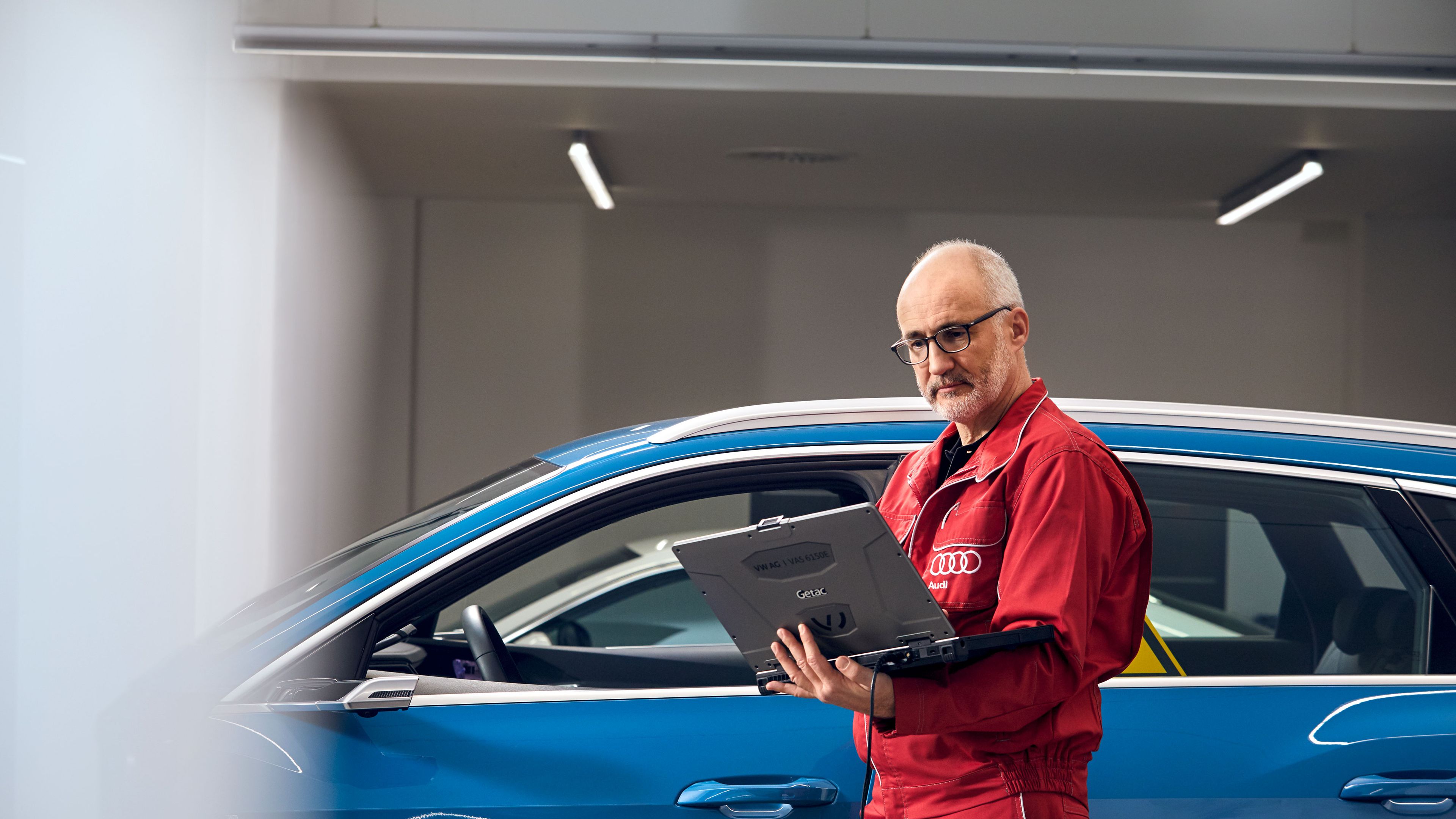 Ein Audi Service Techniker mit Laptop vor einem Audi
