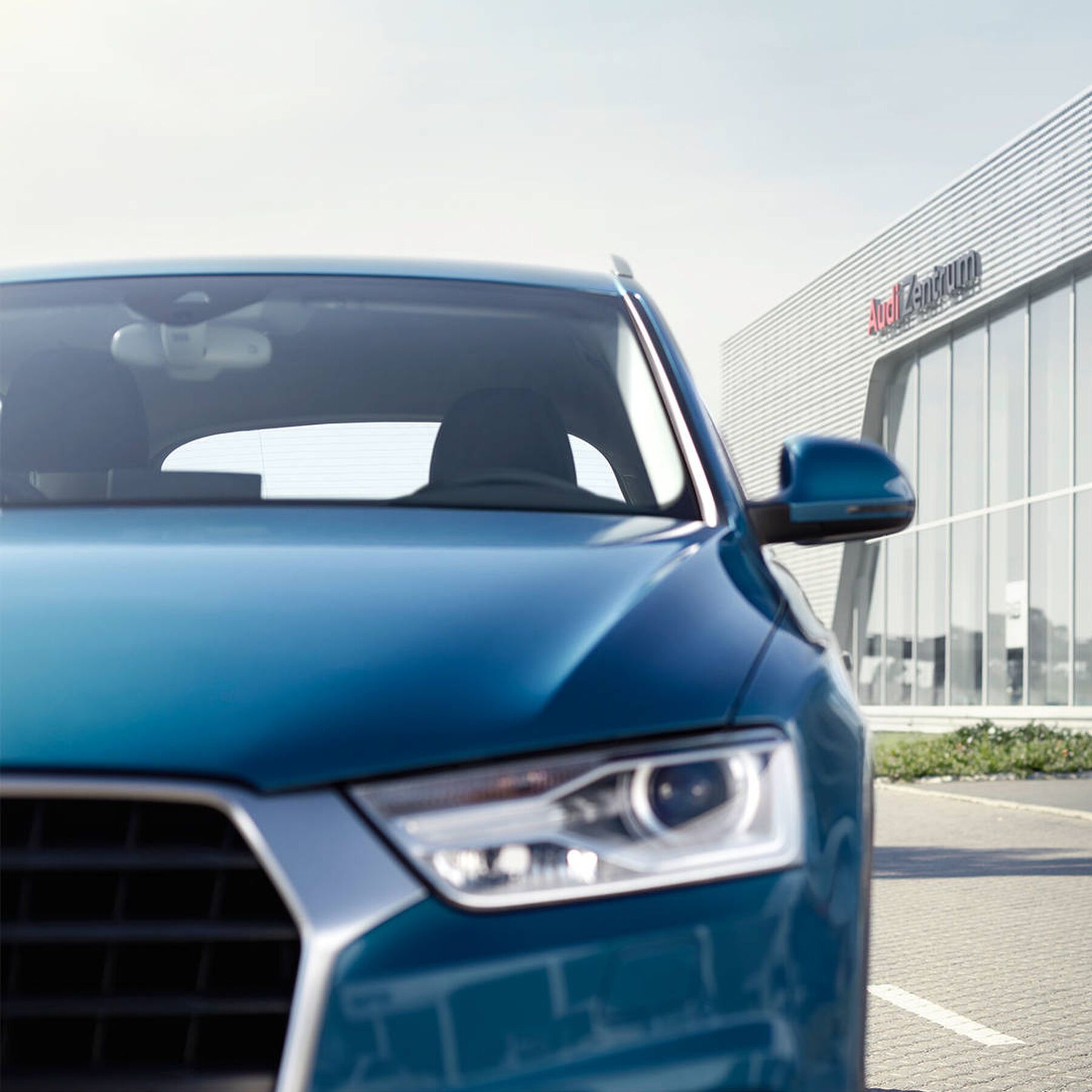 Ein Audi Service Mitarbeiter übergibt einer Kundin den Schlüssel zu ihrem blauen Audi
